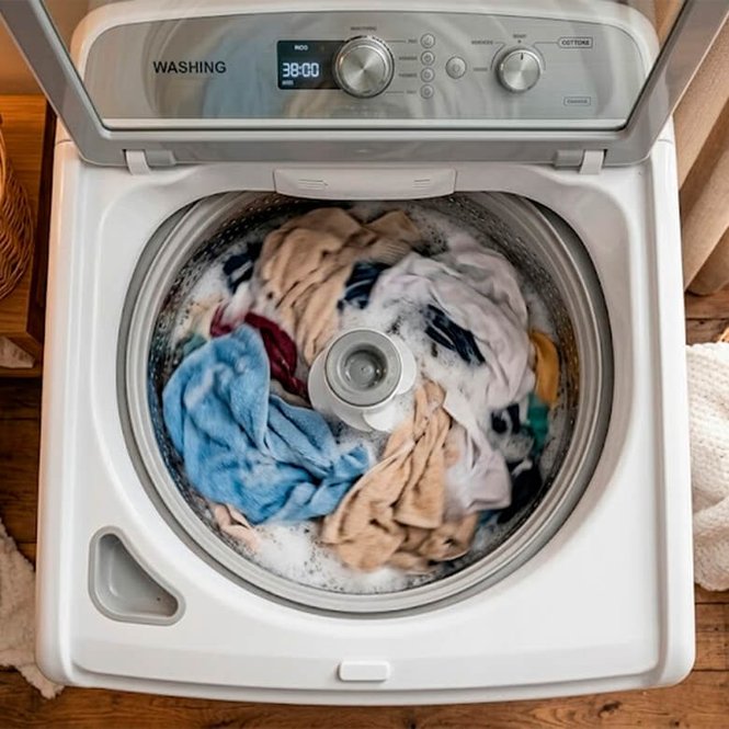 Máquina de lavar roupas aberta com peças coloridas e espuma de Amaciante Comfort Puro Cuidado