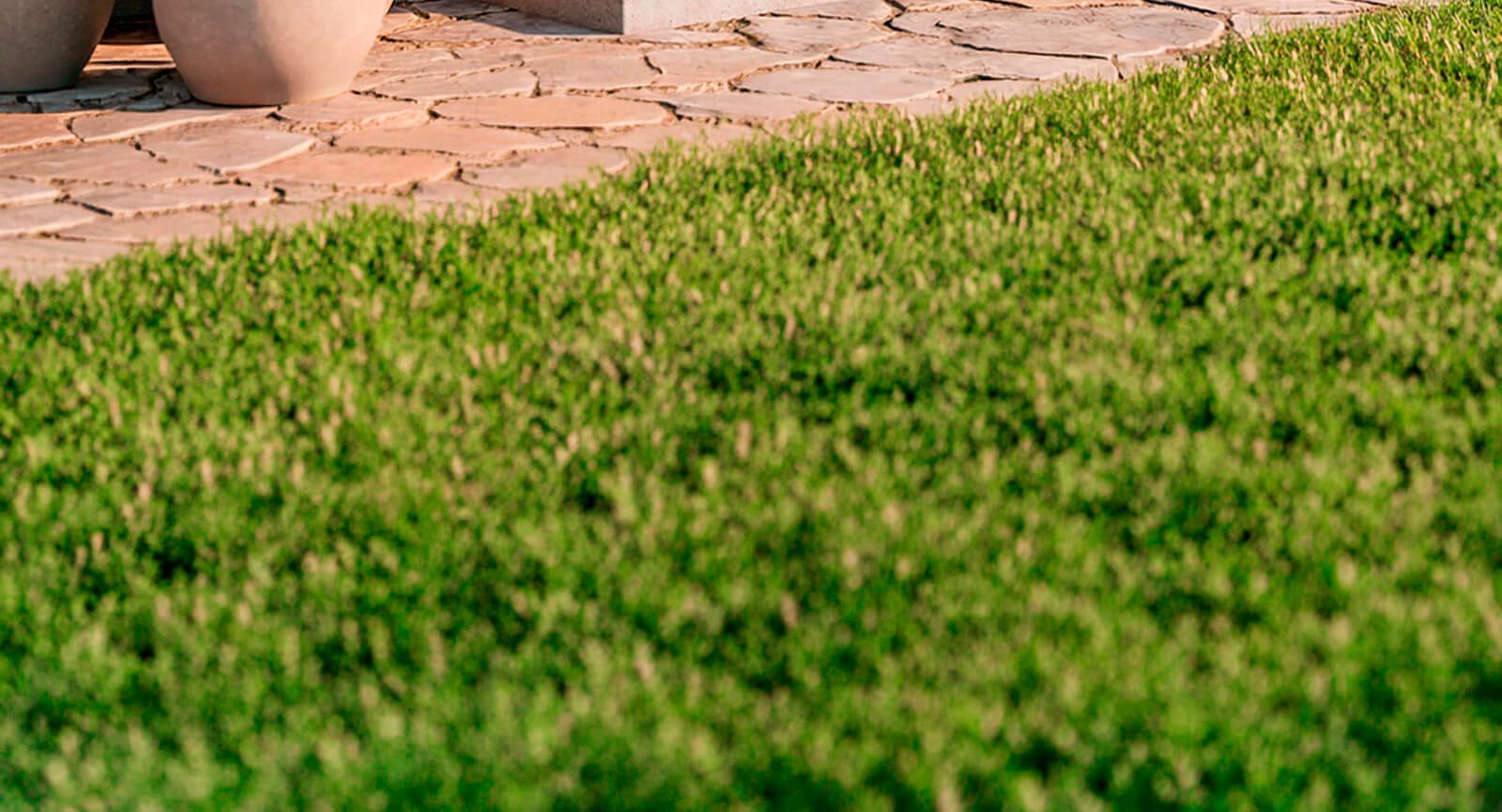 Grama verde e piso de pedra compondo cenário externo do ar-condicionado Elgin Eco Inverter III.