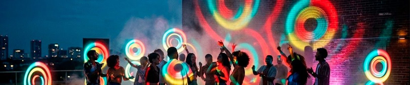Pessoas dançando em festa ao ar livre com luzes coloridas e Caixa de Som Philips Party Speaker