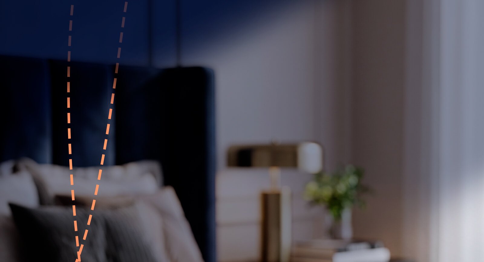Ambiente de quarto desfocado com abajur e cama com linhas tracejadas em V Nadir Ravena