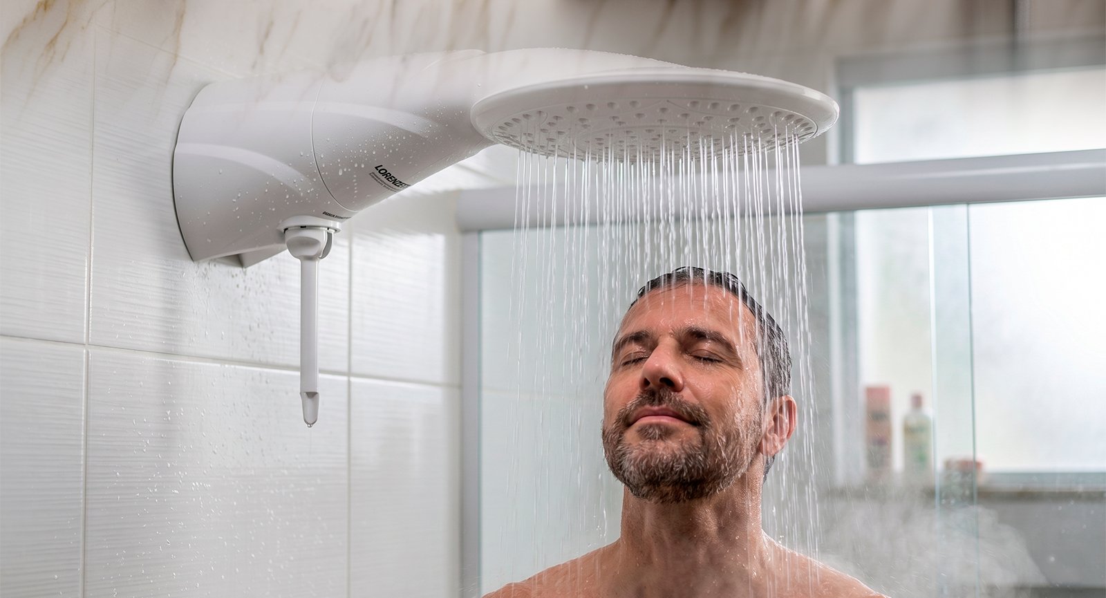 Homem sorrindo de olhos fechados em banho com vapor sob grande espalhador de Ducha Eletrônica Lorenzetti Advanced.