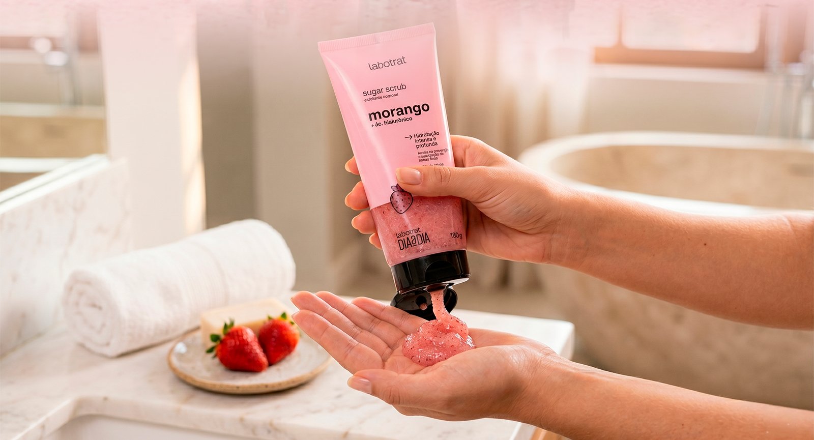 Pessoa aplicando Esfoliante Sugar Scrub Morango Labotrat no braço em ambiente de banheiro