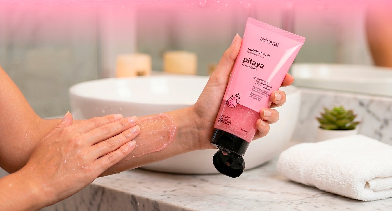 Pessoa aplicando Esfoliante Sugar Scrub Pitaya Labotrat no braço em ambiente de banheiro