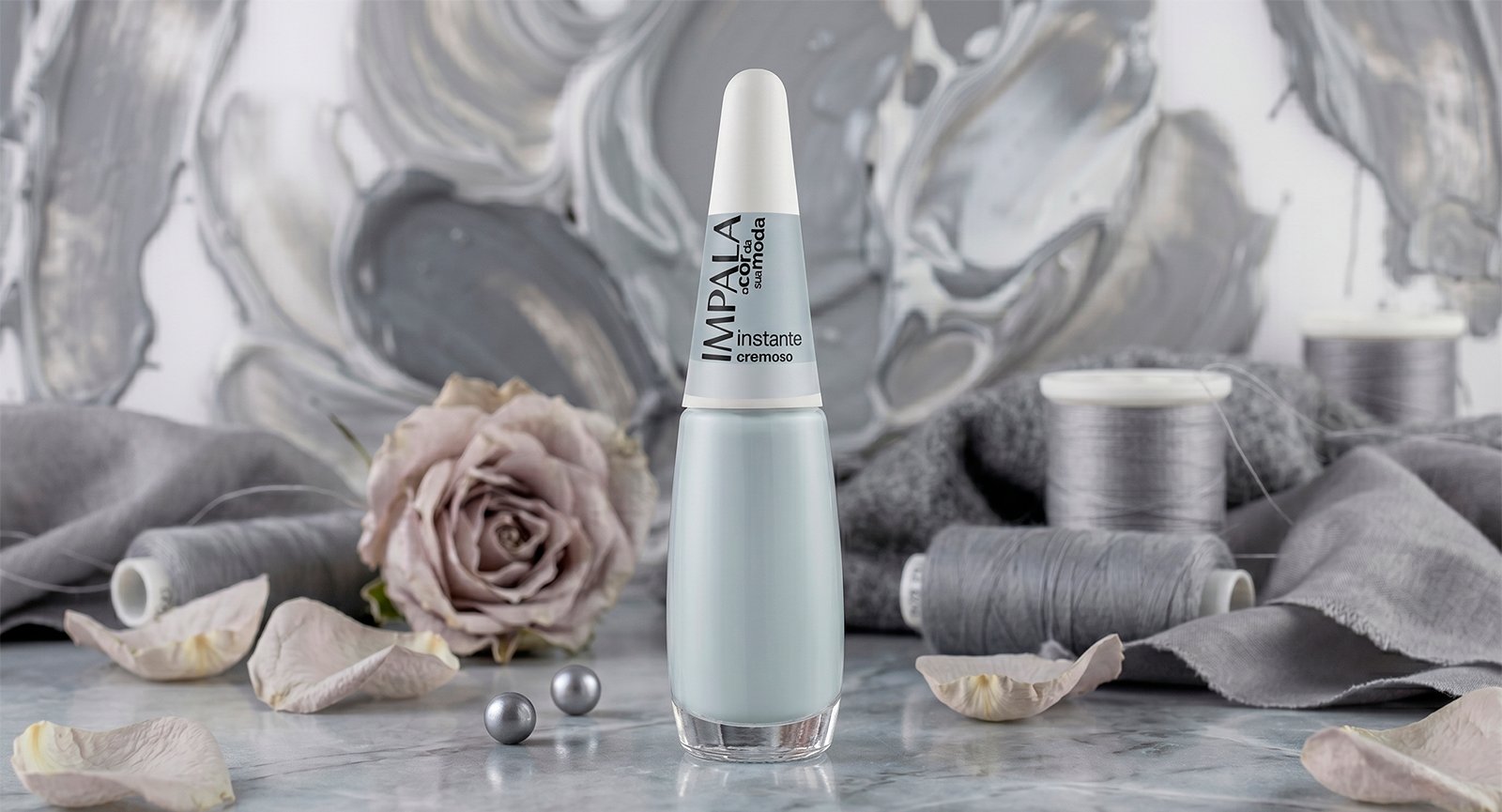 Esmalte Impala Instante cinza claro cremoso em cenário neutro com rosa, pérolas e linhas