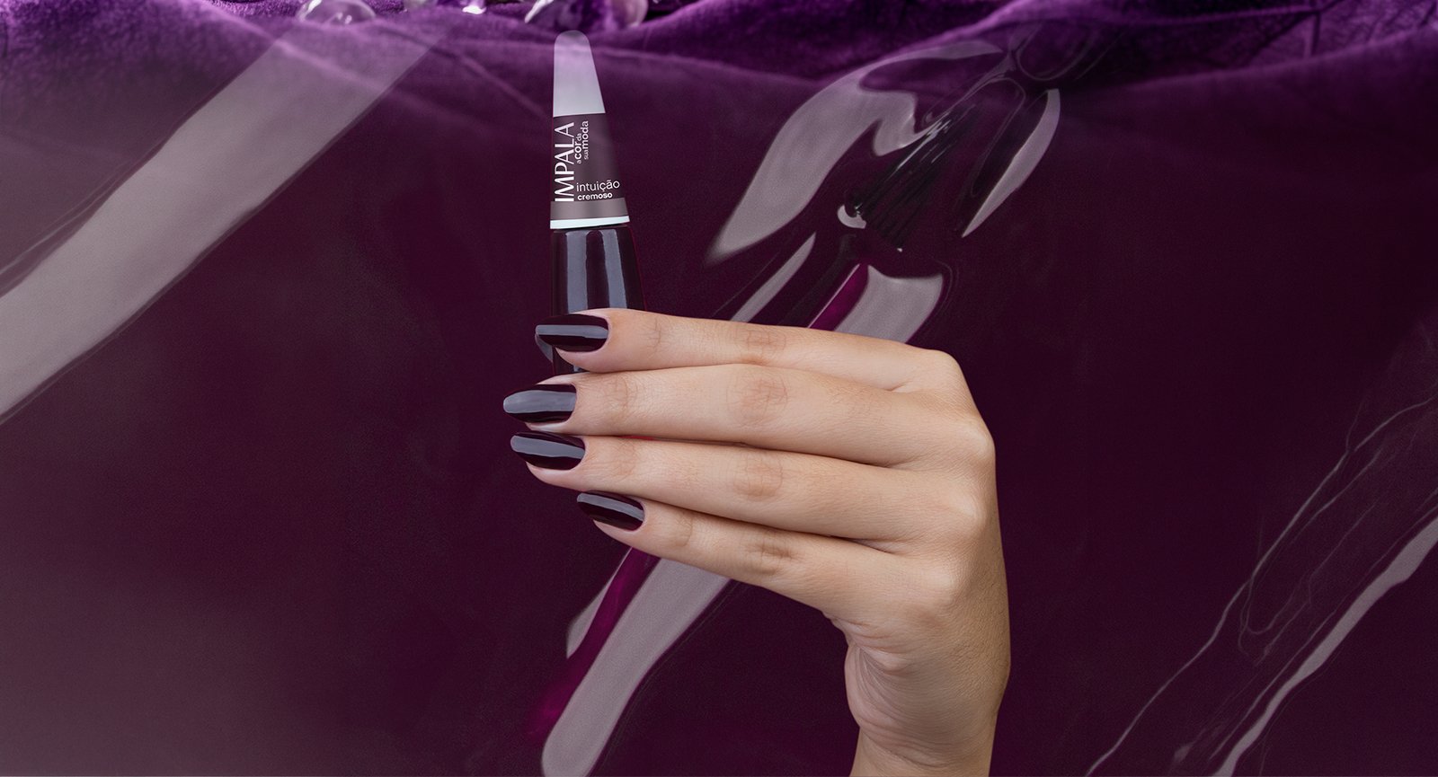 Mão segurando Esmalte Impala Intuição cremoso aplicado em unhas longas com fundo textura roxa