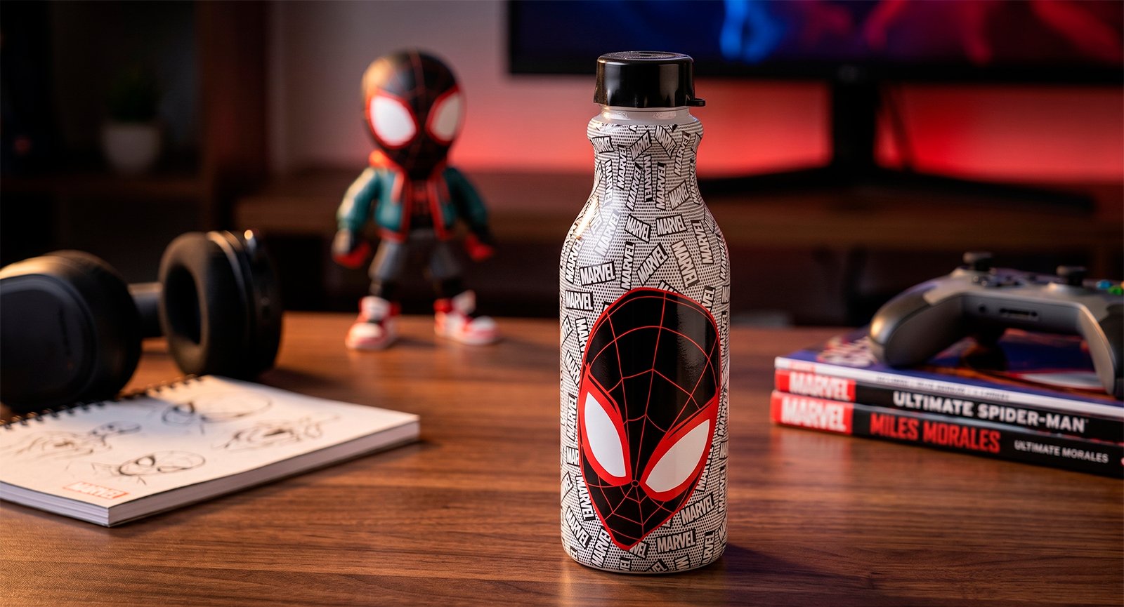 Garrafa Plasútil Retrô Homem Aranha 500ml sobre mesa com controle de videogame e quadrinhos Marvel