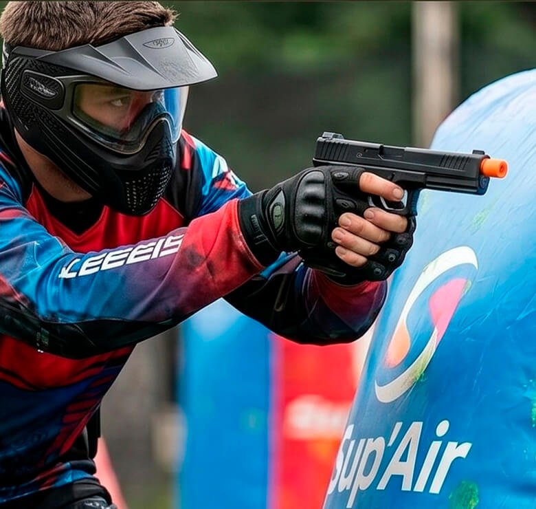 Jogador com máscara mirando Pistola Rossi Vesta em barricada de paintball.
