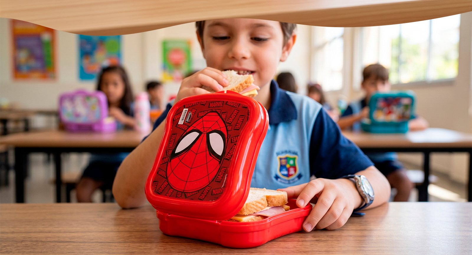 Menino na escola sorrindo comendo sanduíche com o Pote Plasútil Homem-Aranha aberto na mesa