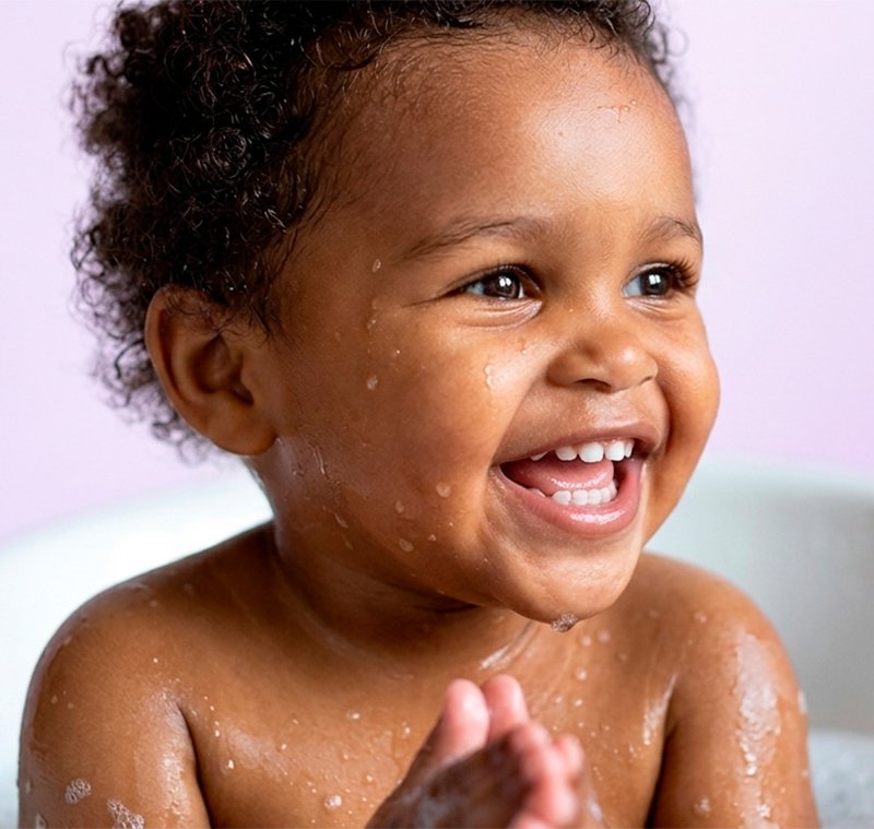 Bebê sorrindo durante banho com espuma, cuidado e relaxamento com Johnson's Baby