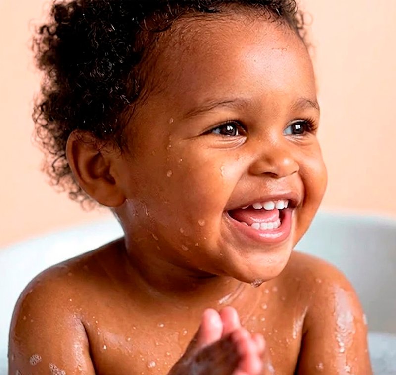 Bebê sorrindo durante banho com Johnson's Baby, limpeza suave e proteção para pele delicada