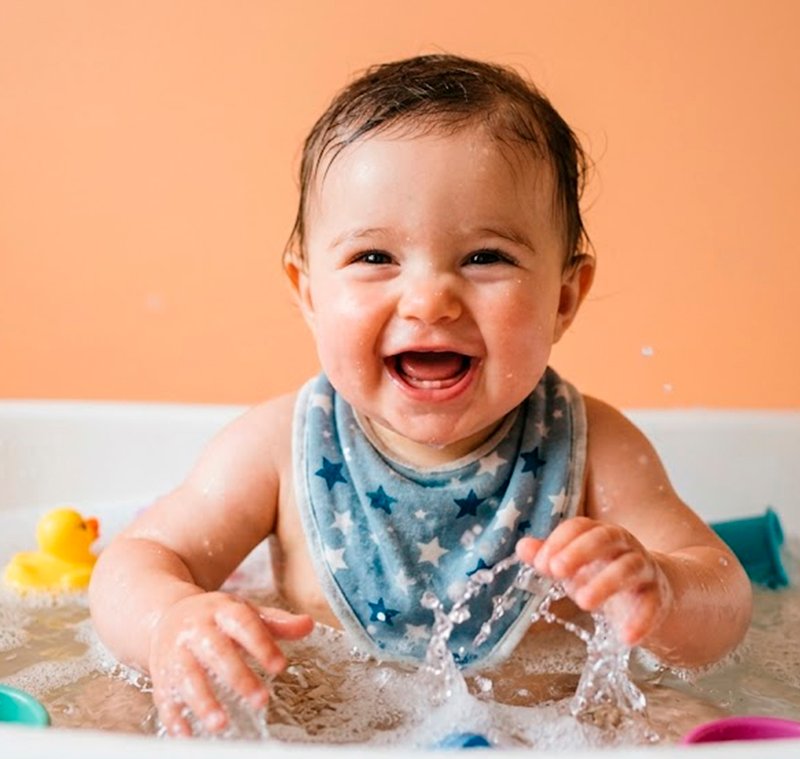 Bebê feliz brincando com água na banheira usando Johnson's Baby — fórmula Chega de Lágrimas