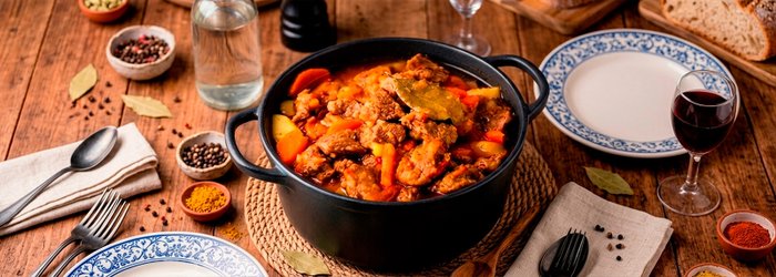 Panela com ensopado de carne e legumes temperado com Kitano em mesa posta com especiarias